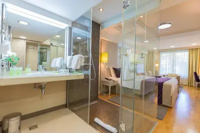 a bathroom with a shower and a sink and a bedroom at Hotel M in Belgrade