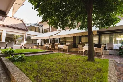 a patio with tables and chairs and a tree at Hotel M in Belgrade