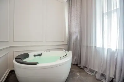 a bathroom with a large white tub in front of a window at Ben Akiba Luxury Suites in Belgrade