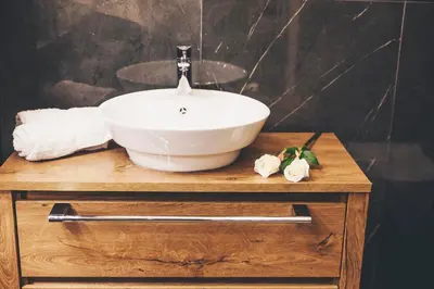 a white bowl sink on a wooden table with towels at Ben Akiba Luxury Suites in Belgrade