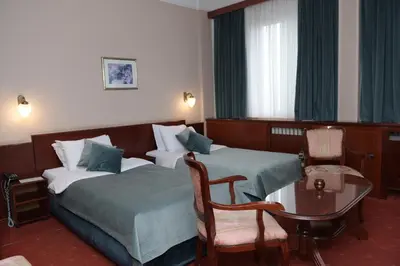 a hotel room with two beds and a table and chairs at Palace Hotel in Belgrade