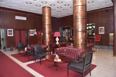 a lobby with a couch and chairs and columns at Palace Hotel in Belgrade