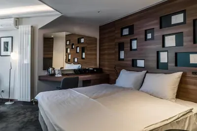 a bedroom with a large bed with a wooden wall at Best Western Premier Natalija Residence in Belgrade