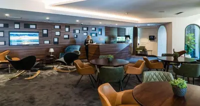 a lobby with tables and chairs and a person in the background at Best Western Premier Natalija Residence in Belgrade