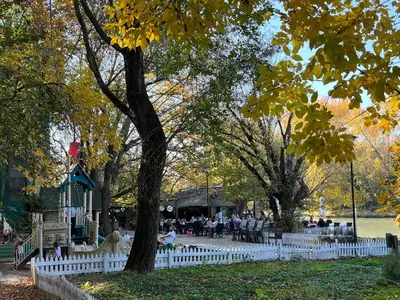 a white picket fence in a park with a tree at Charming Vacation House in Belgrade