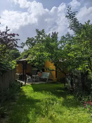 a yard with a yellow house with a tree at Charming Vacation House in Belgrade