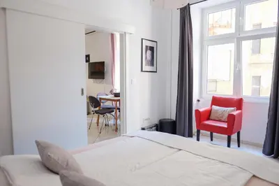 a bedroom with a bed and a red chair and a window at Apartment Luna Terazije in Belgrade