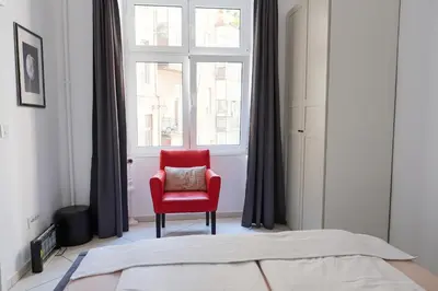 a bedroom with a red chair in front of a window at Apartment Luna Terazije in Belgrade