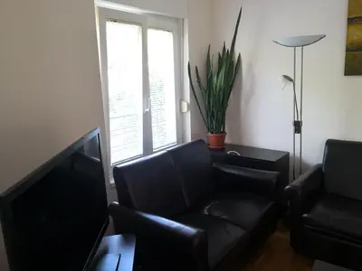 a living room with a black leather couch and a window at Ana's Apartment in Belgrade