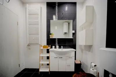 a bathroom with a white sink and black tiles at Ring Inn Apartments in Obrenovac