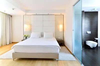 a bedroom with a white bed and a bathroom at Belgrade Art Hotel, a member of Radisson Individuals in Belgrade