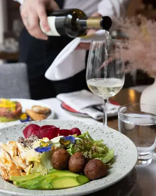 a person pouring white wine into a plate of food at Belgrade Art Hotel, a member of Radisson Individuals in Belgrade