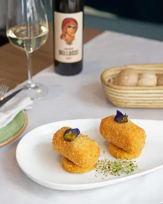 three donuts on a plate with a bottle of wine at Belgrade Art Hotel, a member of Radisson Individuals in Belgrade