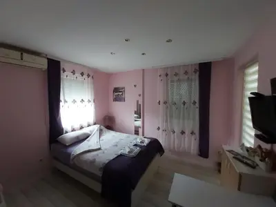 a bedroom with a bed with pink walls and windows at Keti 1 in Belgrade