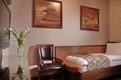 a bedroom with a bed and a chair and a vase with flowers at Vila Terazije in Belgrade