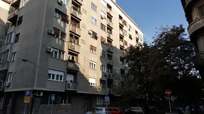 a tall apartment building with cars parked in front of it at Apartment Elza in Belgrade