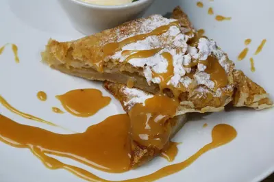 a piece of pie on a white plate with syrup at Garni Hotel Chicha - Winery ŠKRBIĆ in Belgrade
