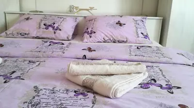 a purple bed with two sheets and towels on it at Apartment Aqua Royal in Arandjelovac