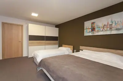 a bedroom with two beds and a painting on the wall at Chess Apartments in Belgrade