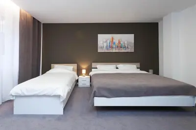 a bedroom with two beds and a painting on the wall at Chess Apartments in Belgrade