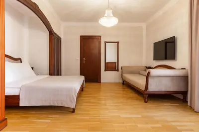 a bedroom with two beds and a couch and a television at Hotel Majestic in Belgrade