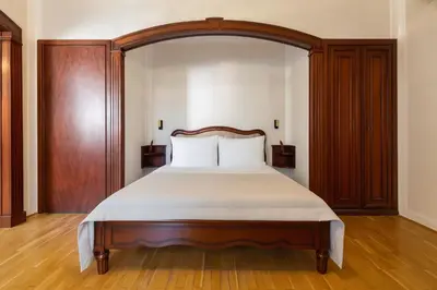 a bedroom with a large bed with a wooden headboard at Hotel Majestic in Belgrade