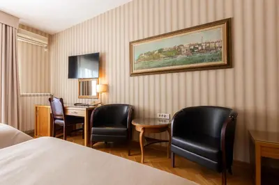 a hotel room with a bed and a desk and chairs at Hotel Majestic in Belgrade