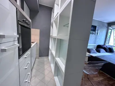 a kitchen with white cabinets and a living room at BASE Accommodation Apartments in Belgrade