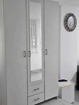 a white cabinet with a mirror in a room at Studio Dana in Arandjelovac