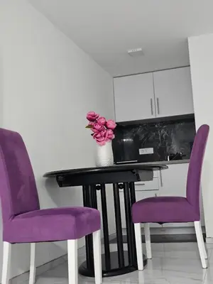 a table with purple chairs and a vase of flowers at Studio Dana in Arandjelovac