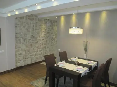 a dining room with two tables and a stone wall at Genex Apartment in Belgrade