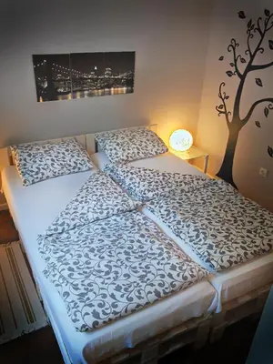 two beds in a room with a tree on the wall at Banshill Apartment in Belgrade