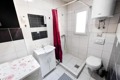a white bathroom with a toilet and a sink at Central Monument Apartment Bojkovic in Belgrade
