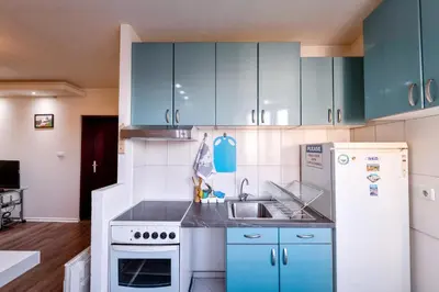 a kitchen with blue cabinets and a sink and a refrigerator at Central Monument Apartment Bojkovic in Belgrade