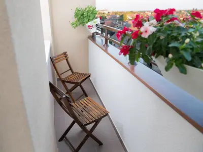 a balcony with a chair and flowers on a balcony at Apartment Koral in Ruma