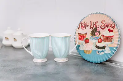 two coffee cups and a plate with cupcakes on it at Apartment Koral in Ruma