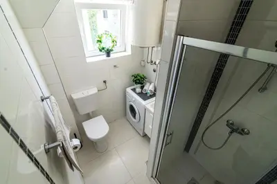 a bathroom with a shower and a toilet and a window at Cozy Central Studio - Steps from Knez Mihailova in Belgrade