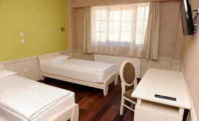 a room with two beds and a table and a window at Hotel Centar Balasevic in Belgrade