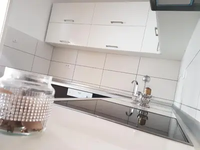 a kitchen with white cabinets and a glass jar on a counter at Apartments Villa White House in Pančevo