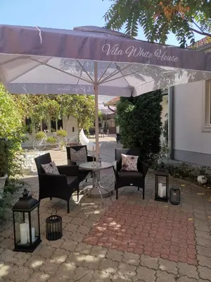 a patio with a table and chairs under an umbrella at Apartments Villa White House in Pančevo
