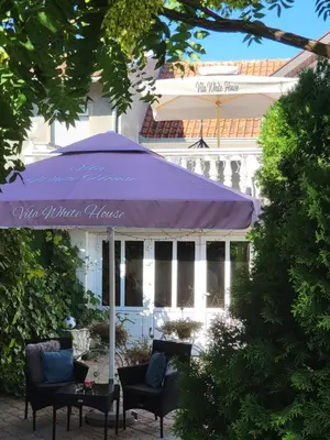 a purple umbrella and chairs in front of a building at Apartments Villa White House in Pančevo