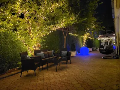 a patio with a couch and chairs and lights at Apartments Villa White House in Pančevo