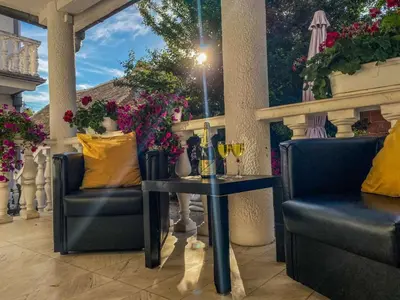 a patio with two chairs and a table and flowers at Apartments Villa White House in Pančevo
