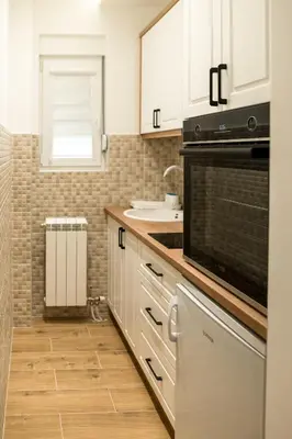 a kitchen with white cabinets and a black oven at President 034 in Arandjelovac