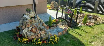 a garden with a fake rock bridge and flowers at President 034 in Arandjelovac