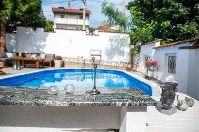 a pool in a backyard with a table and a fountain at Vila Mila in Arandjelovac