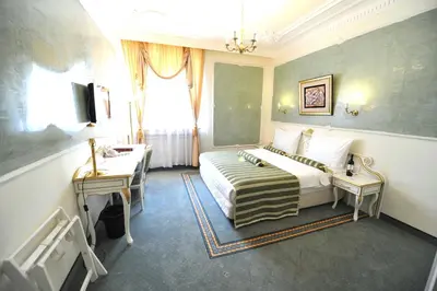 a bedroom with a bed and two tables and a window at Queen's Astoria Design Hotel in Belgrade