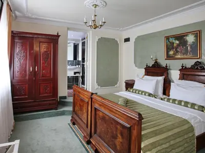 a bedroom with a large bed and a chandelier at Queen's Astoria Design Hotel in Belgrade