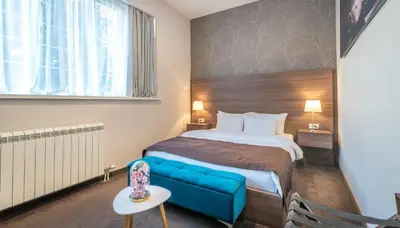 a hotel room with a bed and a blue couch at Veneti Suites in Belgrade