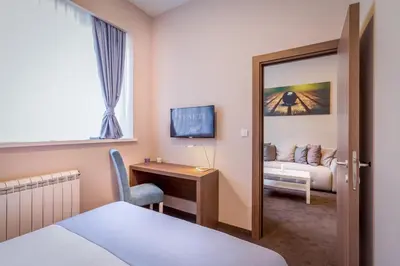 a hotel room with a bed and a desk and a mirror at Veneti Suites in Belgrade